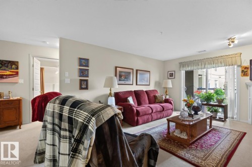 Light-colored walls, carpeted flooring, and a sliding glass door to an exterior space - #210 7909 71 St Nw, Edmonton, AB - Indoor Photo Showing Living Room