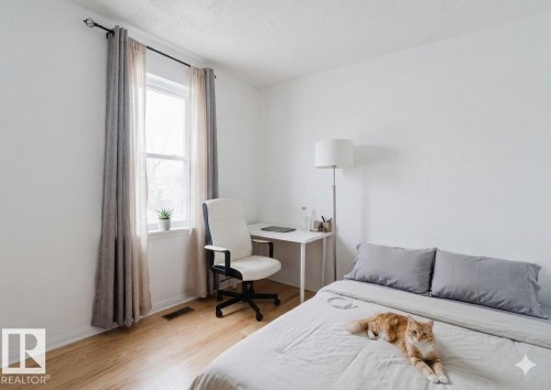 Bright bedroom with hardwood flooring, large window with thermal curtains, and ample natural light - 12223 127 Street Nw, Edmonton, AB - Indoor Photo Showing Bedroom