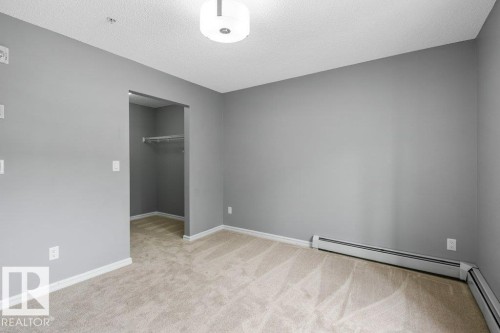 Carpeted flooring with light gray wall paint, a ceiling-mounted light fixture, and a built-in closet with wire shelving - #117 2203 44 Av Nw, Edmonton, AB - Indoor Photo Showing Other Room