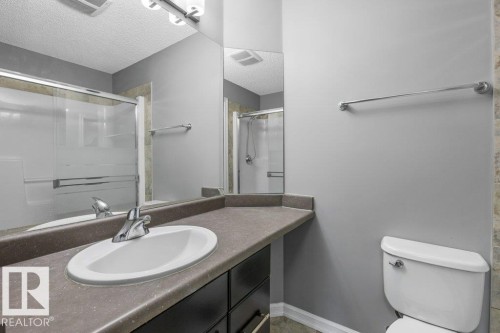 Vanity with integrated sink, chrome faucet, and dark base cabinetry - #117 2203 44 Av Nw, Edmonton, AB - Indoor Photo Showing Bathroom