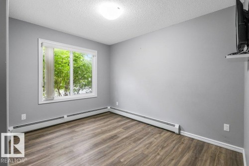 Wood-finish flooring, white trim, and light gray wall color - #117 2203 44 Av Nw, Edmonton, AB - Indoor Photo Showing Other Room