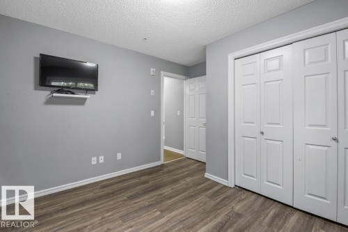 Wood-finish flooring, light gray wall paint, and white trim - #117 2203 44 Av Nw, Edmonton, AB - Indoor Photo Showing Other Room