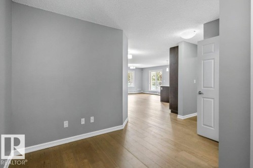 Wood-finish flooring throughout, light gray wall paint, and white trim accents - #117 2203 44 Av Nw, Edmonton, AB - Indoor Photo Showing Other Room