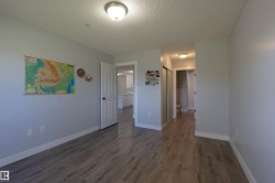 Light gray walls with white trim, wood-finish flooring, a white paneled door, and a flush mount ceiling light - 