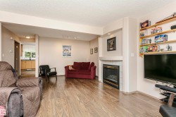 Wood-finish flooring throughout, recessed lighting, and a white tile-surround fireplace with a black insert - 