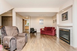Living space featuring wood-finish flooring, a white tiled fireplace, and a built-in recessed ceiling light - 