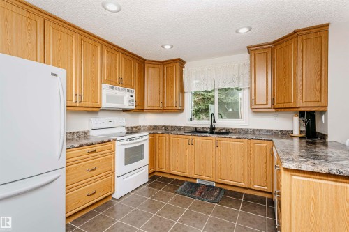 U-shaped kitchen with wood-finish cabinetry, tile flooring, and recessed lighting - #42 9630 176 St Nw, Edmonton, AB - Indoor Photo Showing Kitchen