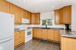U-shaped kitchen with wood-finish cabinetry, tile flooring, and recessed lighting - 