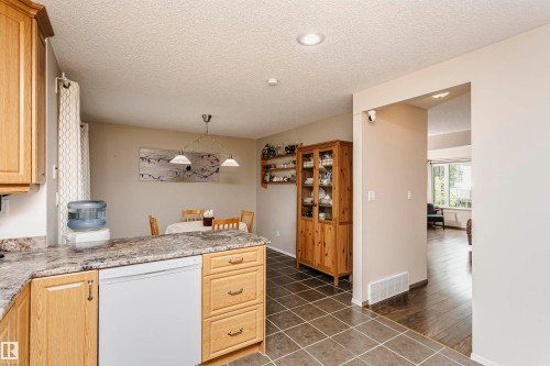 Kitchen featuring light wood cabinetry, stone-look countertops, and a built-in dishwasher - #42 9630 176 St Nw, Edmonton, AB - Indoor Photo Showing Kitchen