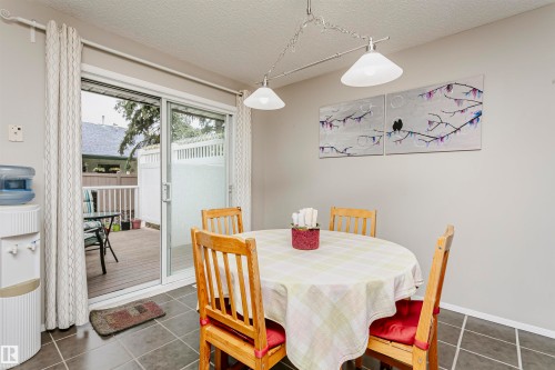 Sliding glass patio door, exterior deck, tile flooring, and a ceiling-mounted light fixture - #42 9630 176 St Nw, Edmonton, AB - Indoor Photo Showing Dining Room