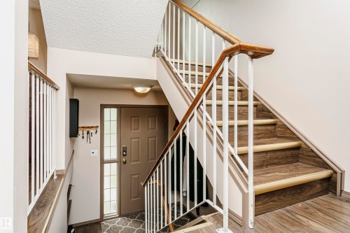 Staircase featuring wood-finish treads, white risers, and a matching wood-finish handrail - #42 9630 176 St Nw, Edmonton, AB - Indoor Photo Showing Other Room