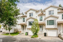 Townhome exterior with light-colored siding, multiple windows, attached garage, and prominent front entry - 