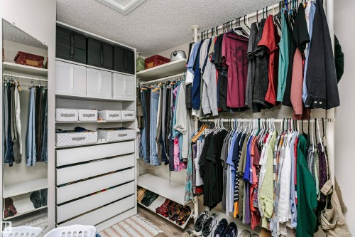 Custom built-in closet system featuring multiple hanging rods, integrated shelving, and white drawer storage - #42 9630 176 St Nw, Edmonton, AB - Indoor With Storage