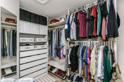 Custom built-in closet system featuring multiple hanging rods, integrated shelving, and white drawer storage - 