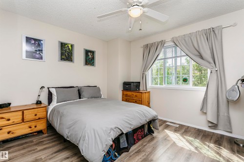 Wood-finish flooring, white walls, and a multi-pane window with white blinds - #42 9630 176 St Nw, Edmonton, AB - Indoor Photo Showing Bedroom