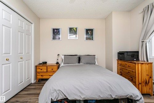 Wood-finish flooring, white bi-fold closet doors, and neutral wall paint - #42 9630 176 St Nw, Edmonton, AB - Indoor Photo Showing Bedroom