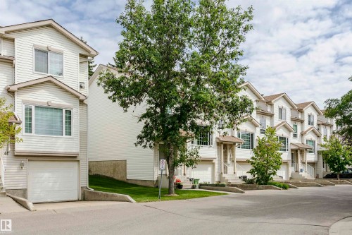 Row of townhomes featuring light-colored siding, multiple windows, and individual garage doors - #42 9630 176 St Nw, Edmonton, AB - Outdoor With Facade
