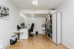 Light wood-finish flooring, white walls, built-in shelving, white paneled door, and recessed lighting - 