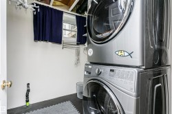 Laundry area with white walls and dark flooring - 