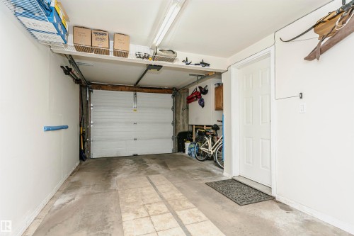Single-car garage with concrete flooring, overhead fluorescent lighting, and a paneled entry door - #42 9630 176 St Nw, Edmonton, AB - Indoor Photo Showing Garage