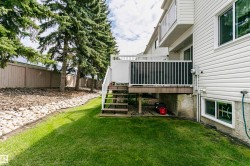 Rear exterior with white vinyl siding, a wood-finish deck with white railings, and a concrete foundation with a basement window - 