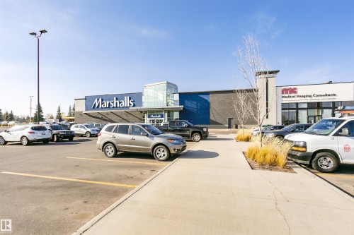 Retail storefront featuring a prominent Marshalls sign, an additional medical imaging consultant office, a large paved parking lot, and a concrete walkway with planted grass - #42 9630 176 St Nw, Edmonton, AB - Outdoor
