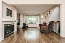 Fireplace with white tile surround, wood-finish flooring, large multi-pane window, built-in shelving, and recessed lighting - 