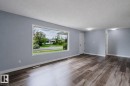 Spacious room featuring wood-finish flooring, a large picture window, and light blue painted walls - 11420 46 Avenue Nw, Edmonton, AB  - Indoor Photo Showing Other Room 