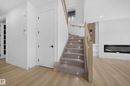 Light wood-finish flooring complements the modern interior - 8915 Mayday Way Sw, Edmonton, AB - Indoor Photo Showing Other Room