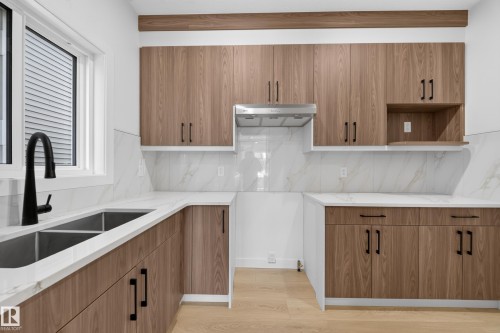 Wood-finish cabinetry with matte black hardware, white countertops, stainless steel undermount double sink, and a black gooseneck faucet - 8915 Mayday Way Sw, Edmonton, AB - Indoor Photo Showing Kitchen With Double Sink