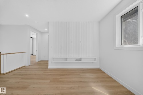Wood-finish flooring with recessed lighting, a built-in media console, and a white framed window - 8915 Mayday Way Sw, Edmonton, AB - Indoor Photo Showing Other Room