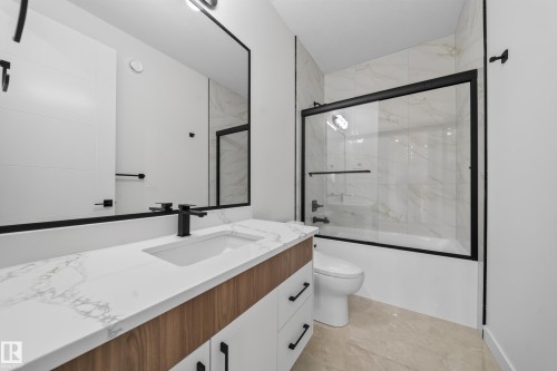 Contemporary bath featuring a vanity with wood-grain and white cabinetry, a white countertop with integrated sink, and a matte black faucet - 8915 Mayday Way Sw, Edmonton, AB - Indoor Photo Showing Bathroom