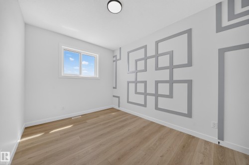 Wood-finish flooring throughout, bright white walls, and a recessed window - 8915 Mayday Way Sw, Edmonton, AB - Indoor Photo Showing Other Room