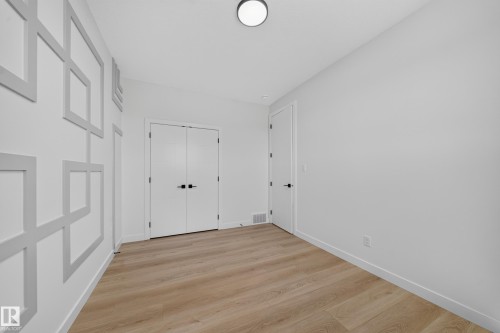 Accent wall with geometric trim, wood-finish flooring, recessed lighting, and double-door entry - 8915 Mayday Way Sw, Edmonton, AB - Indoor Photo Showing Other Room