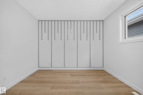 Light wood-finish flooring, white walls, and a single window with white trim - 8915 Mayday Way Sw, Edmonton, AB - Indoor Photo Showing Other Room