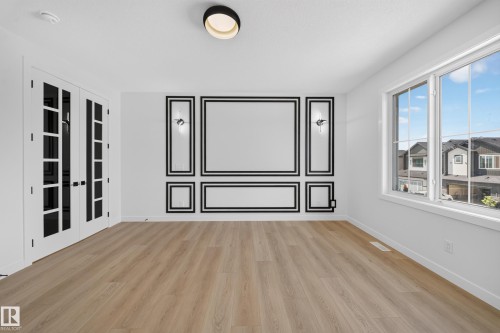 Wood-finish flooring, white walls with decorative black trim, twin glass-paneled doors with black hardware, and large multi-pane windows - 8915 Mayday Way Sw, Edmonton, AB - Indoor Photo Showing Other Room