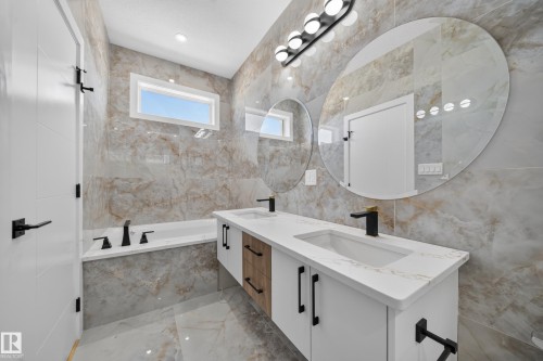 Bathroom featuring a double vanity with integrated sinks, quartz countertop, and black fixtures - 8915 Mayday Way Sw, Edmonton, AB - Indoor Photo Showing Bathroom