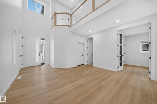 Two-story foyer with high ceilings, wood-finish flooring, and natural light from transom windows - 8915 Mayday Way Sw, Edmonton, AB - Indoor Photo Showing Other Room
