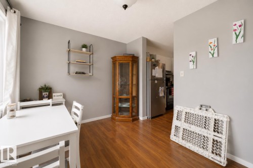 Hardwood-finish flooring, light gray wall color, built-in corner cabinet, visible kitchen with stainless steel refrigerator, white trim - #44 1415 62 St Nw, Edmonton, AB - Indoor
