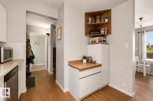 Wood-finish flooring throughout, white shaker-style cabinetry, light-toned countertops, and built-in corner shelving - #44 1415 62 St Nw, Edmonton, AB - Indoor Photo Showing Other Room