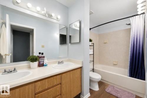 Dual vanity with integrated sinks and wood-finish cabinetry - #44 1415 62 St Nw, Edmonton, AB - Indoor Photo Showing Bathroom