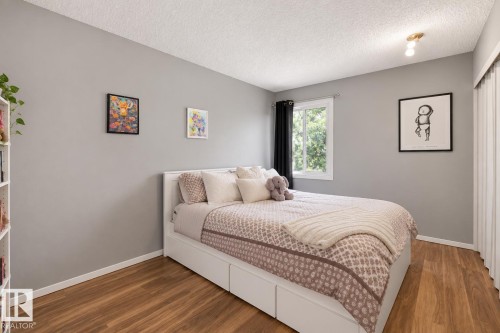 Wood-finish flooring, white window frame, neutral wall color, and built-in closet with bi-fold doors - #44 1415 62 St Nw, Edmonton, AB - Indoor Photo Showing Bedroom