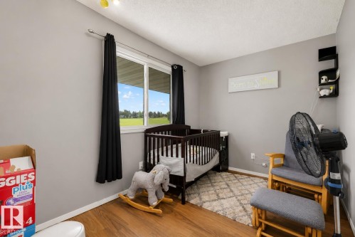Room featuring wood-finish flooring, light grey painted walls, and a window with a green exterior landscape - #44 1415 62 St Nw, Edmonton, AB - Indoor