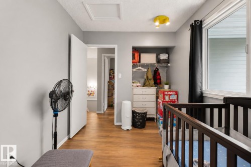 Wood-finish flooring, built-in closet shelving, window with white trim, track lighting, and a ceiling access panel - #44 1415 62 St Nw, Edmonton, AB - Indoor Photo Showing Other Room
