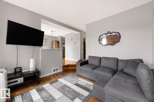 Hardwood flooring, light gray wall finishes, and an upper wall-mounted television - #44 1415 62 St Nw, Edmonton, AB - Indoor Photo Showing Living Room