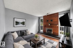 Living room featuring a wood-panel accent wall, built-in fireplace, and wood-finish flooring - 