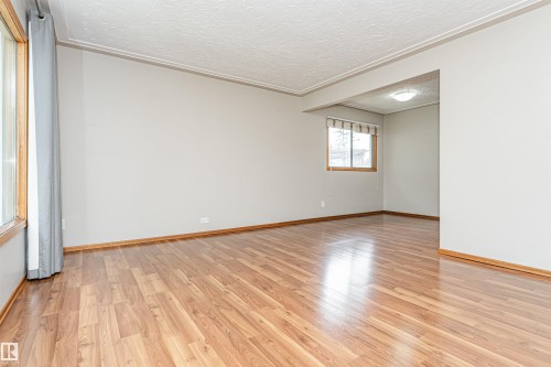 Wood-finish flooring, light neutral wall paint, crown molding, and natural light from multiple windows - 11139 62 Avenue Nw, Edmonton, AB - Indoor Photo Showing Other Room