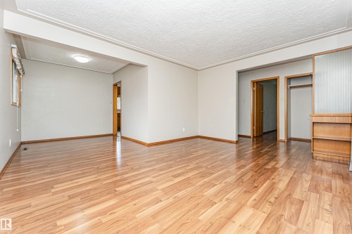 Wood-finish flooring throughout, complemented by crown molding and a built-in shelving unit - 11139 62 Avenue Nw, Edmonton, AB - Indoor Photo Showing Other Room