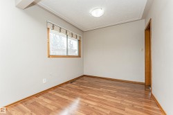 Wood-finish flooring with a light wood baseboard, neutral wall paint, and a window featuring wood trim - 