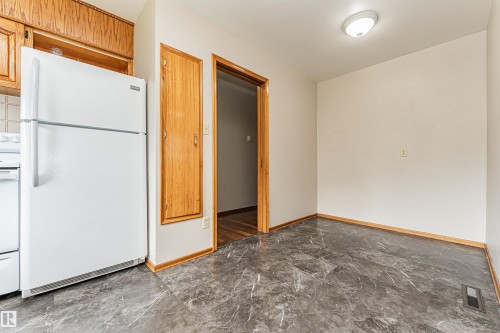 White appliances, wood-finish cabinetry, and dark gray flooring - 11139 62 Avenue Nw, Edmonton, AB - Indoor Photo Showing Other Room